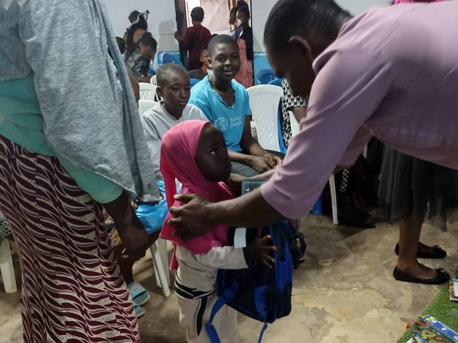 COHEC volunteer helping a child with a new backpack