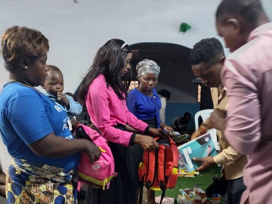 COHEC volunteer handing a backpack to a mother and child