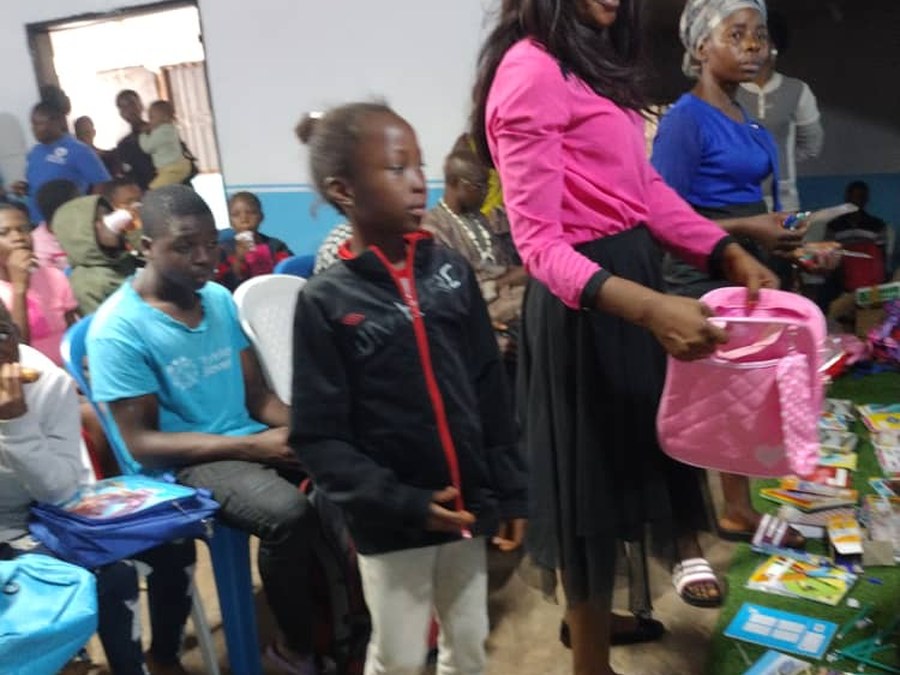 COHEC volunteer handing a backpack to a child